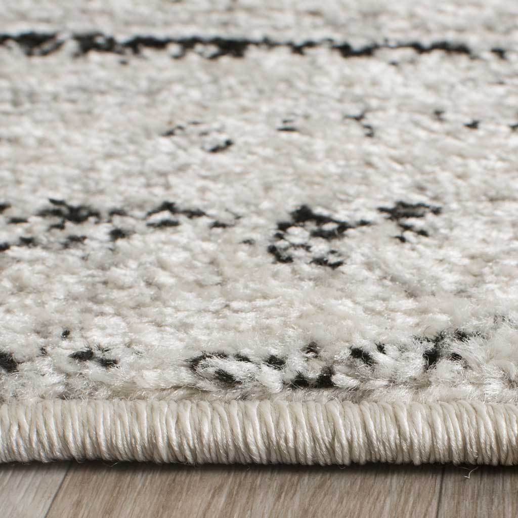 Ivory pile with scattered dark flecks meets a neatly bound edge