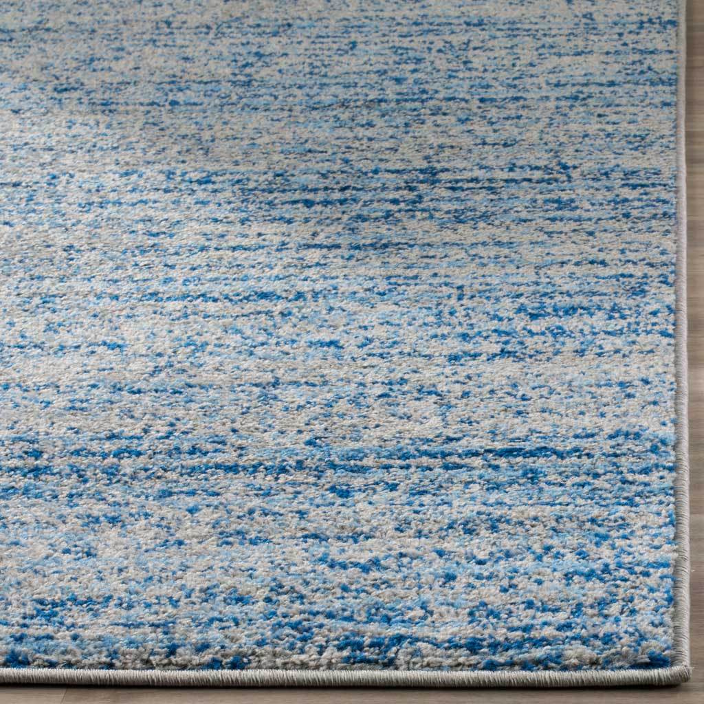 Blue and silver striations flow across a textured pile finished with bound edges