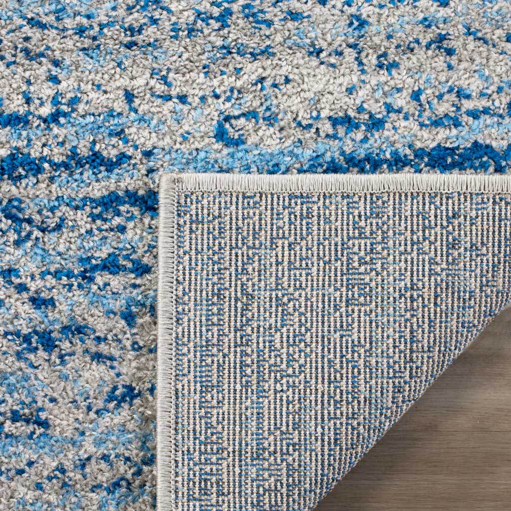 Woven backing and neat binding support the blue and silver rug's soft, patterned pile