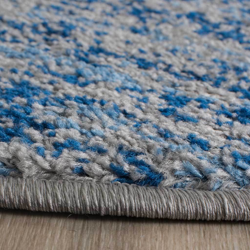 Blue fibers among silver yarns create a textured pile with a clean bound edge