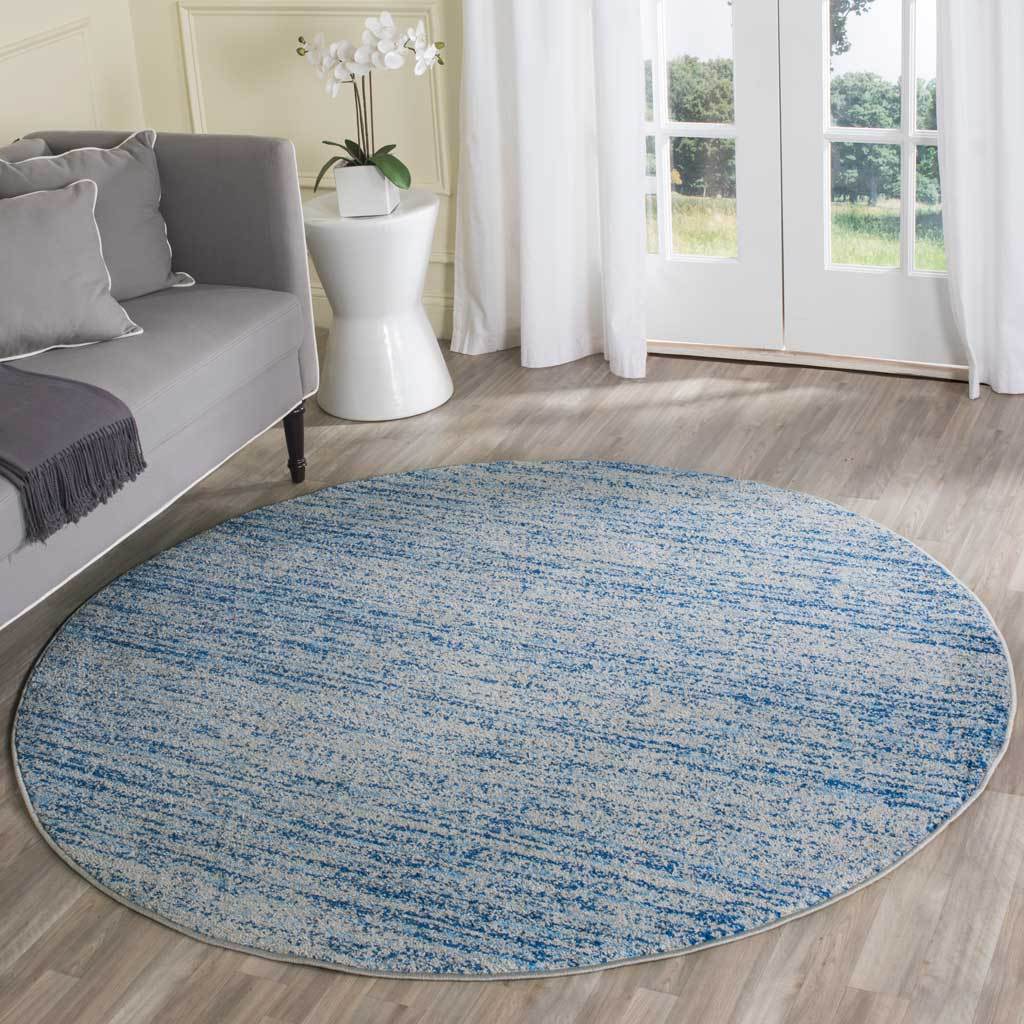 Blue and silver round rug adds relaxed color and texture beside a neutral sofa