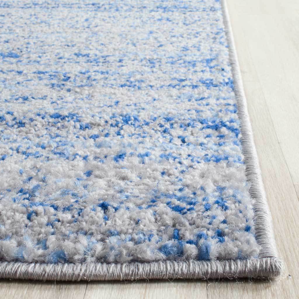 Blue flecks mingle with soft silver pile along a neatly wrapped rug edge