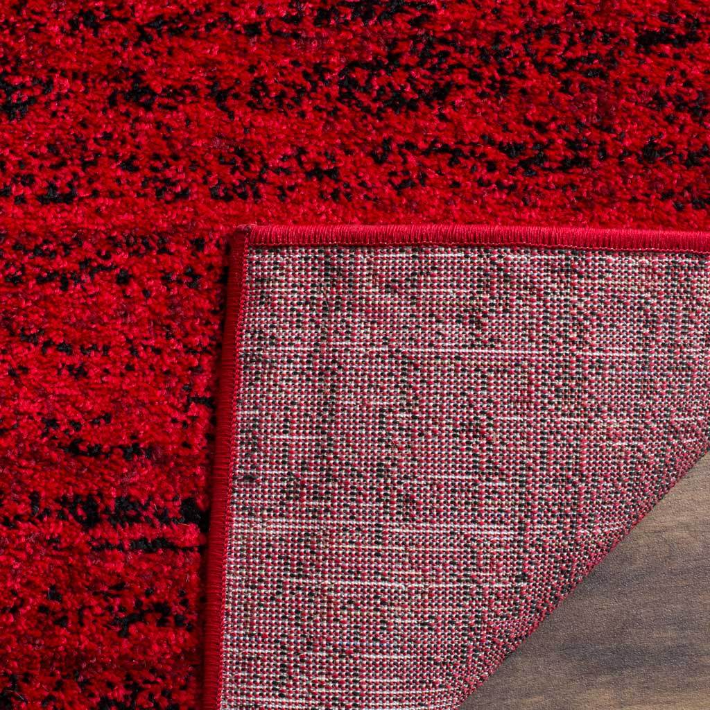 Woven backing and red edge binding support the rug's vivid red and black pile