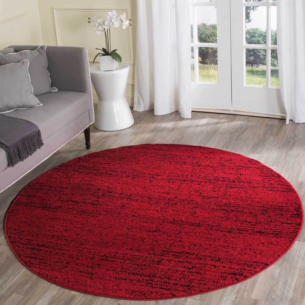 Red and black round rug makes a bold statement in a bright, neutral living room