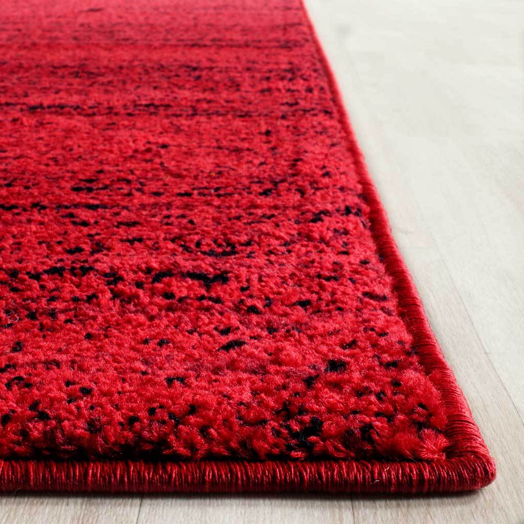 Soft red pile is flecked with black above a neatly wrapped rug edge