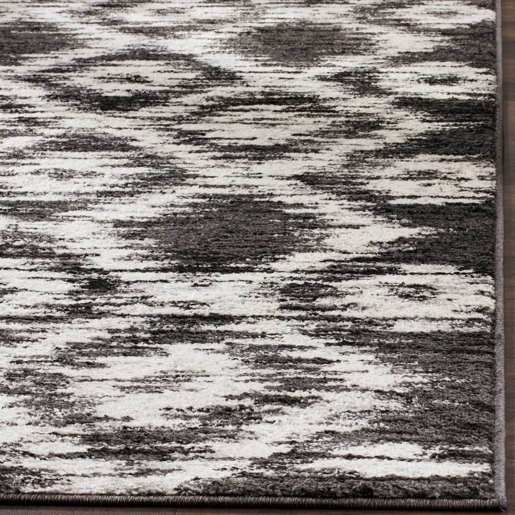 Neatly bound edges frame the rug's charcoal and ivory pattern and textured surface