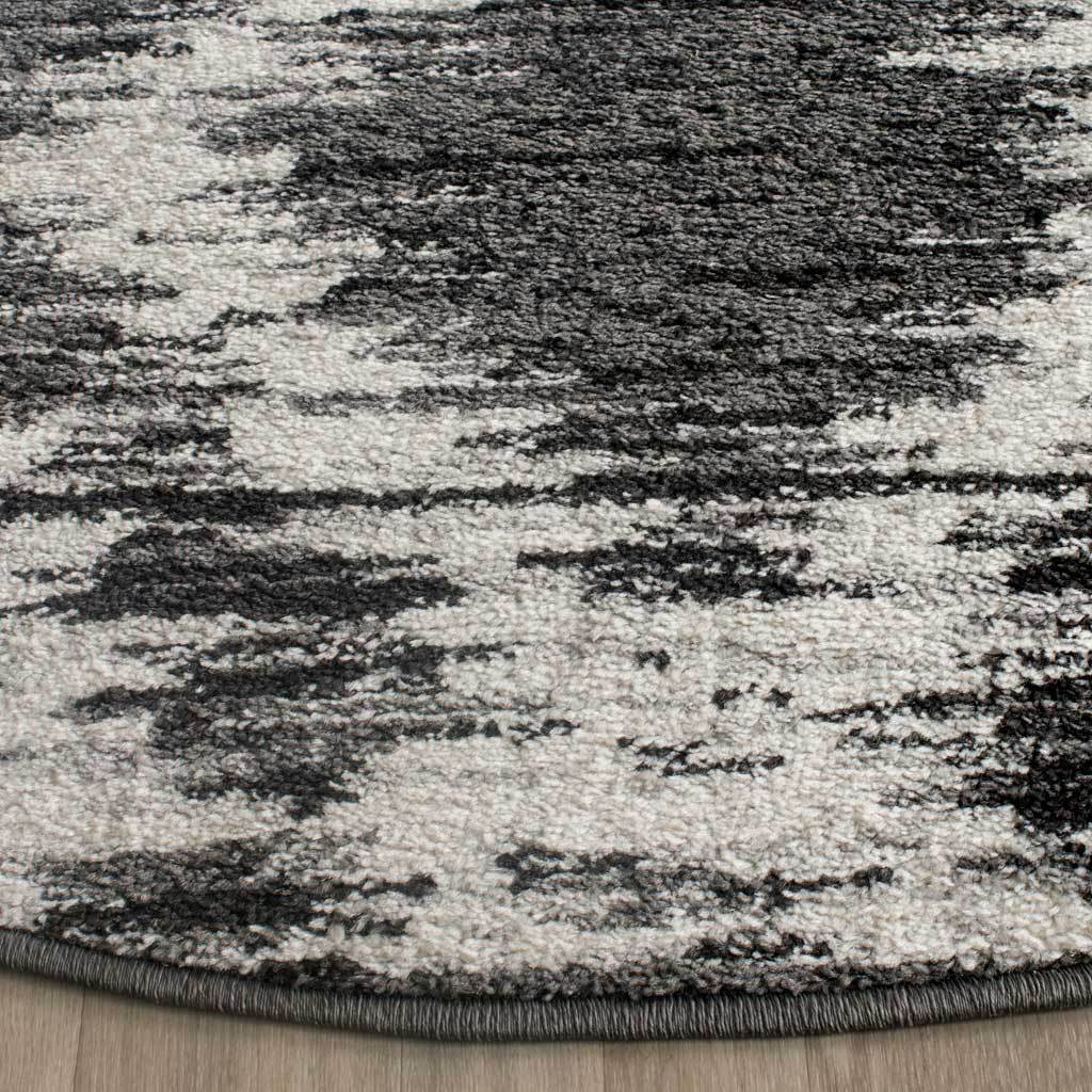 A neatly bound edge finishes the rug's soft, low-pile charcoal and ivory pattern