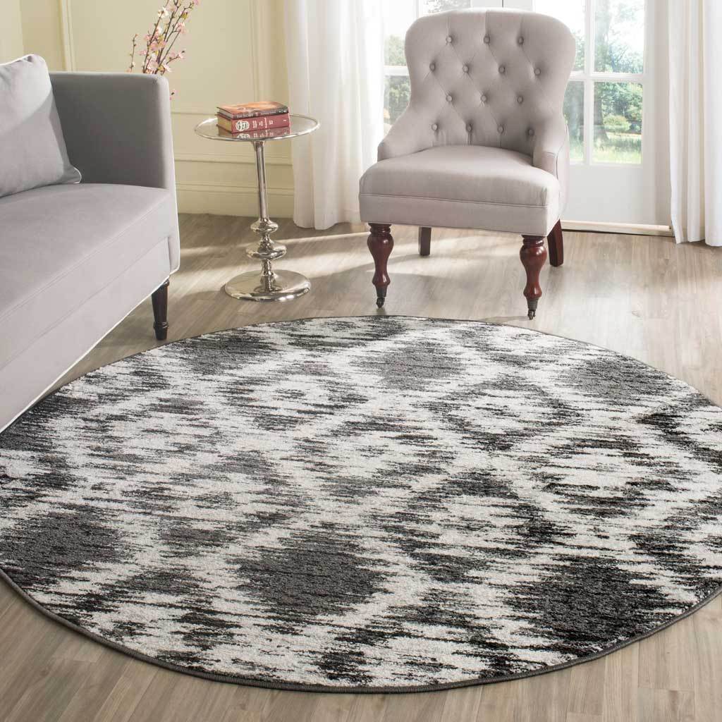 The round rug anchors neutral seating with a bold charcoal and ivory abstract design