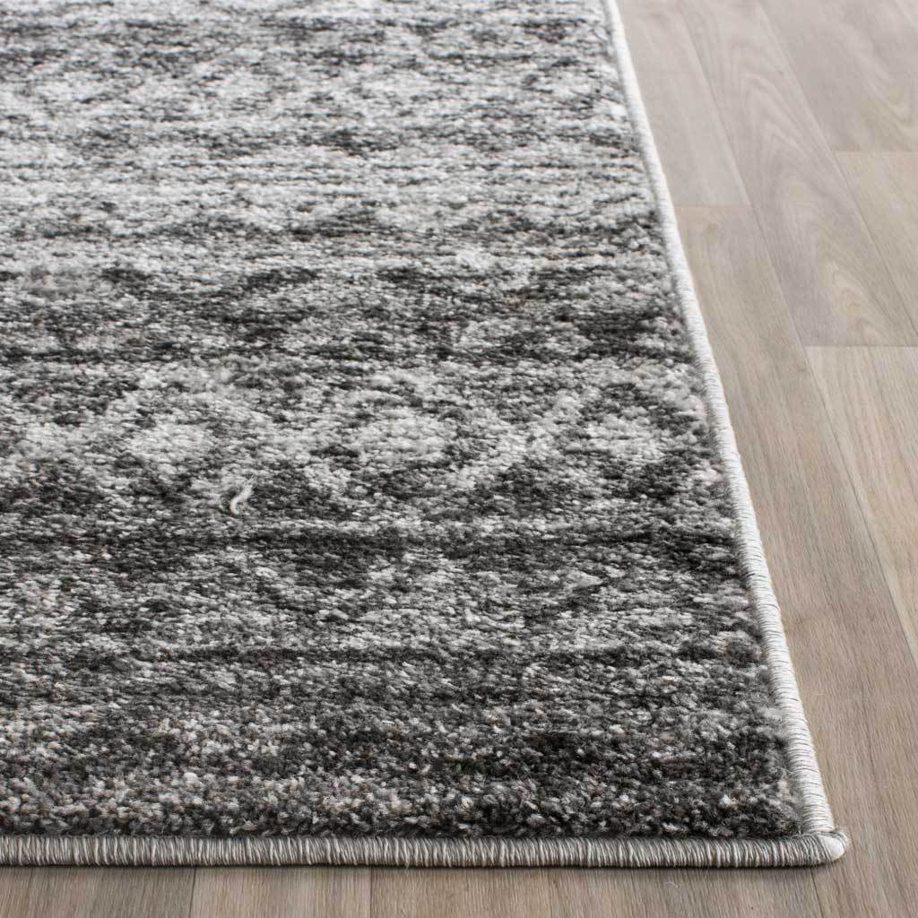 Bound edges finish a textured rug with charcoal and ivory geometric motifs
