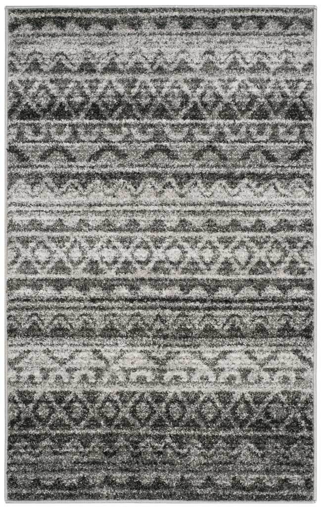 Weathered charcoal motifs trace lively geometric stripes across a compact ivory rug.