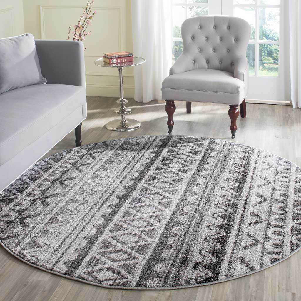 Ivory and charcoal round rug brings bold geometric bands to a bright seating area
