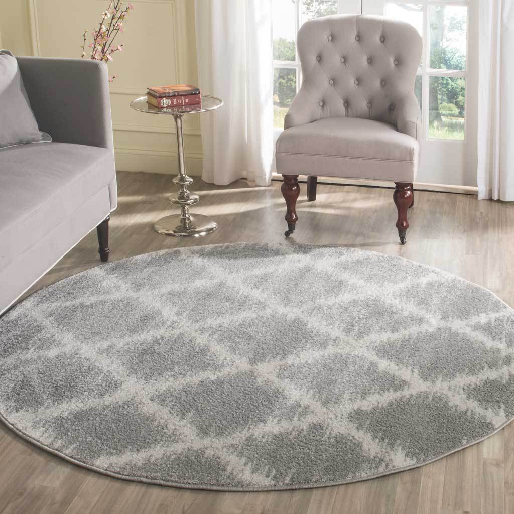A silver and ivory round rug anchors a seating area with a subtle trellis pattern.