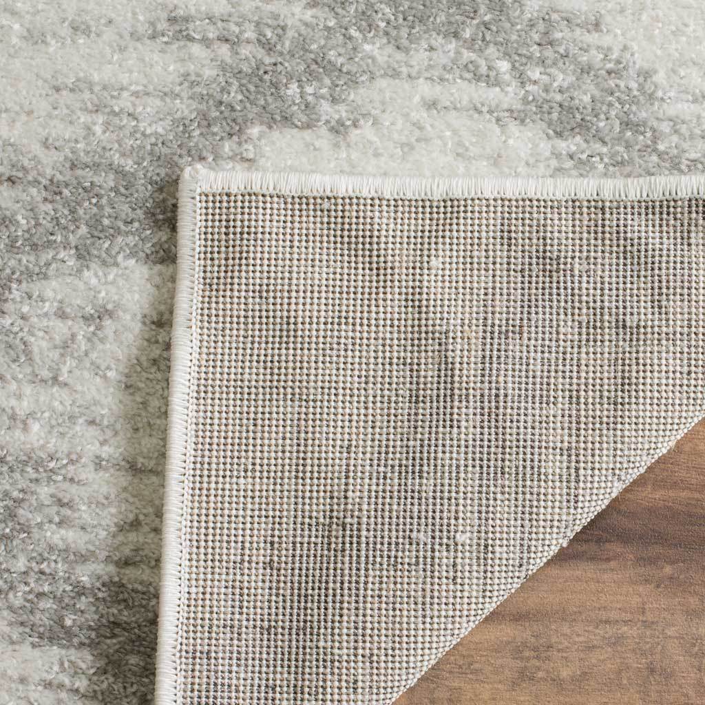 Tightly woven backing supports the ivory and silver rug beneath its neatly bound edge