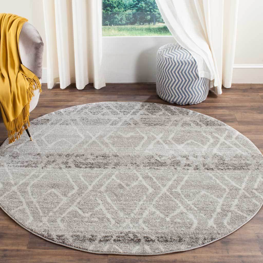 A round silver and ivory rug adds a subtle geometric pattern to a warm wood floor