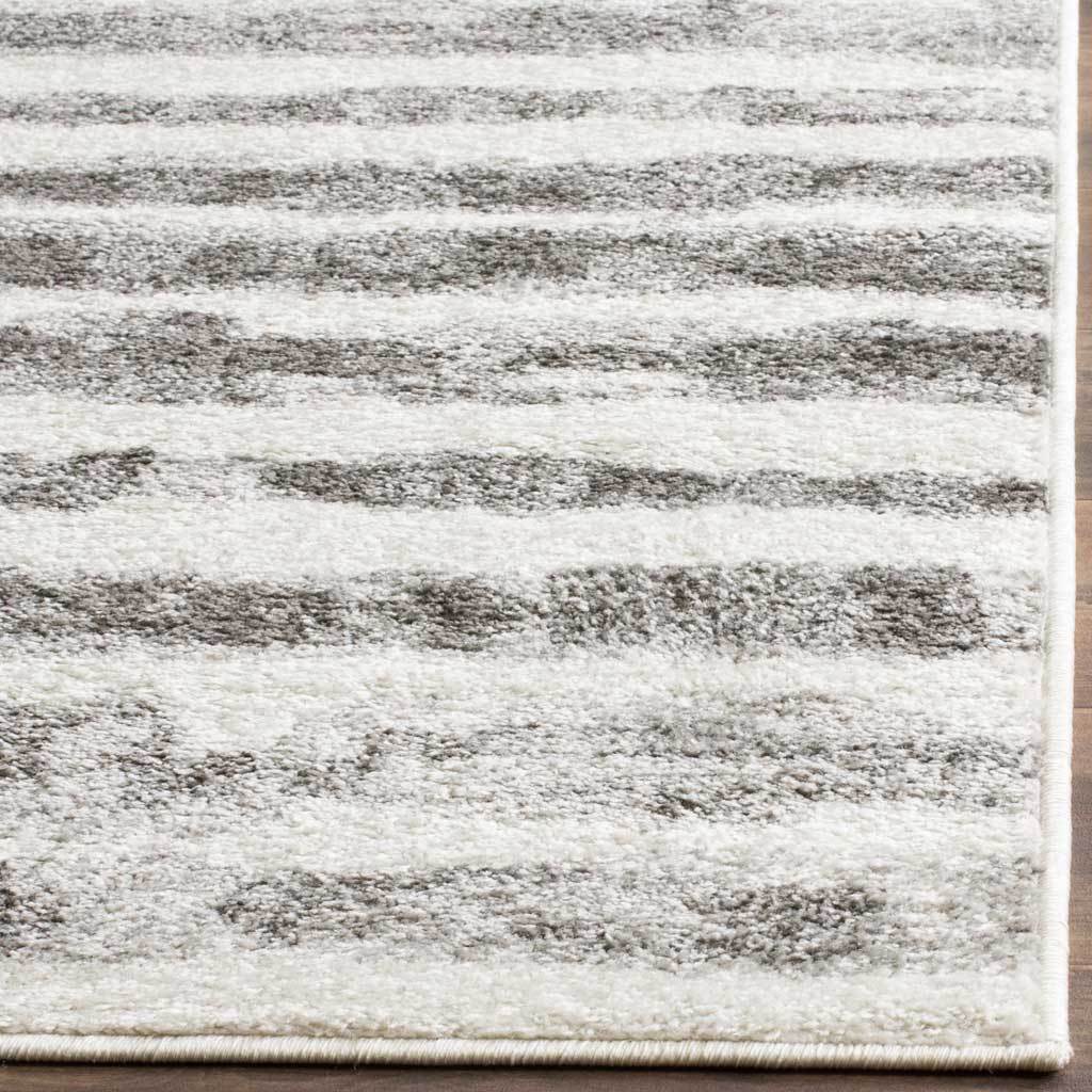 Textured ivory and charcoal stripes meet a neatly finished rug edge