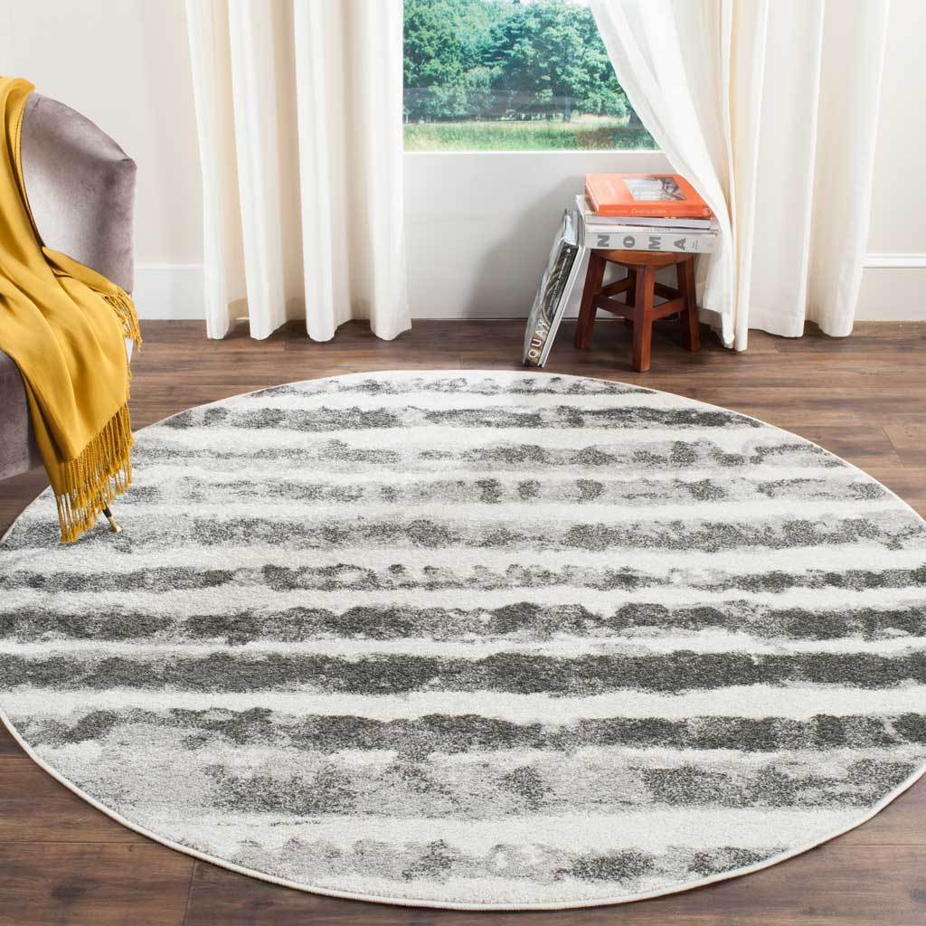 Distressed charcoal stripes lend this round ivory rug a relaxed presence atop warm wood floors.
