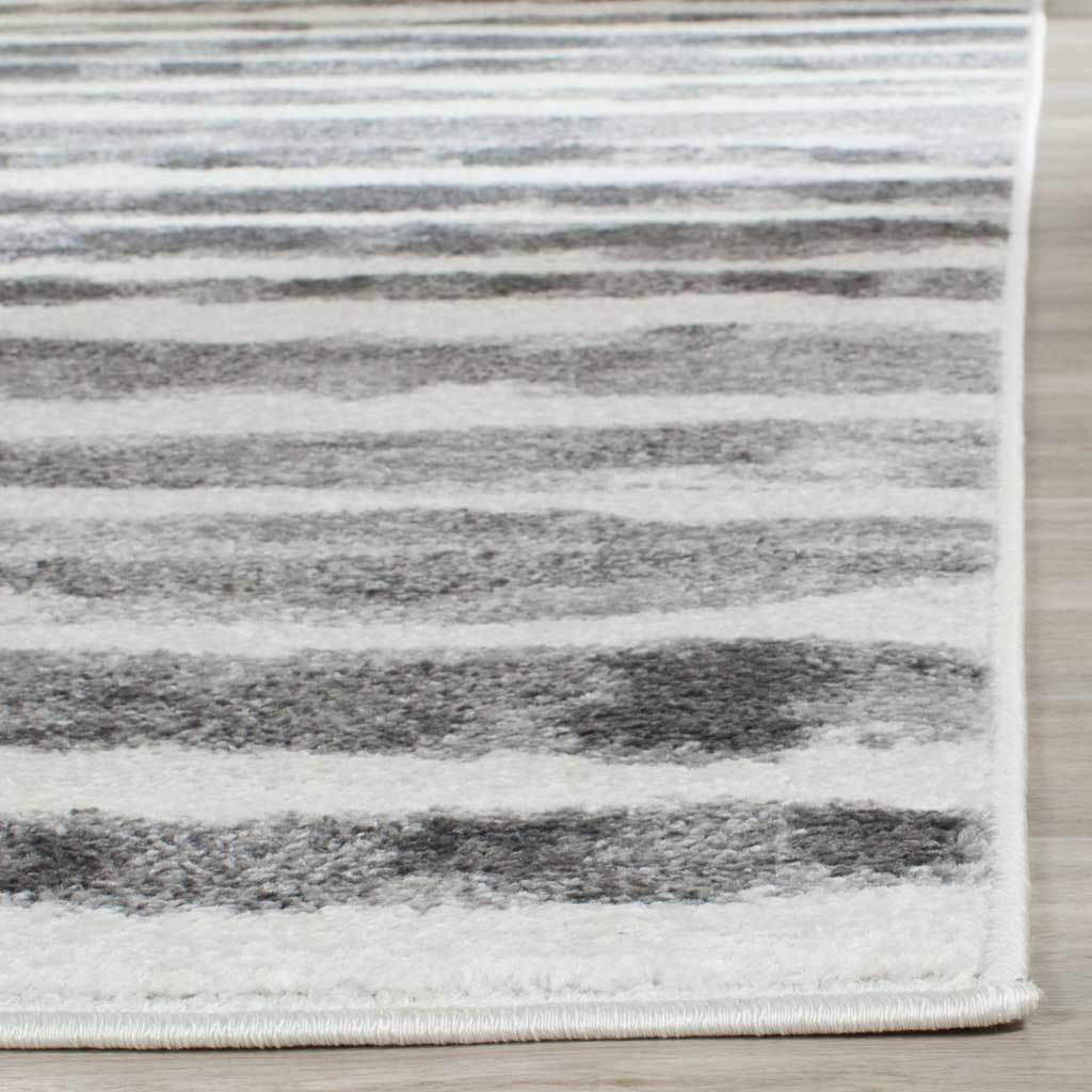 A neatly bound edge frames the rug's textured ivory and charcoal stripes