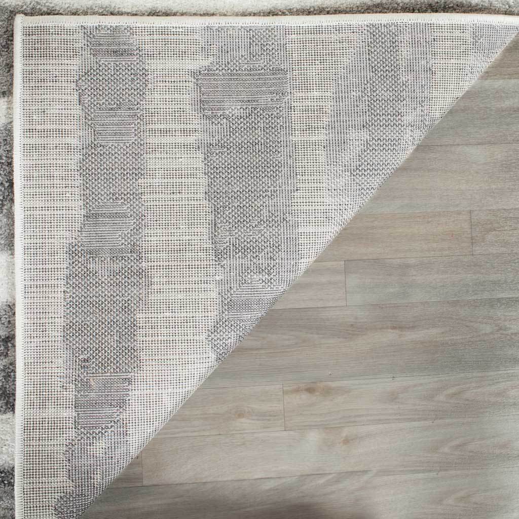 Woven backing and neatly bound edges finish the ivory and charcoal area rug