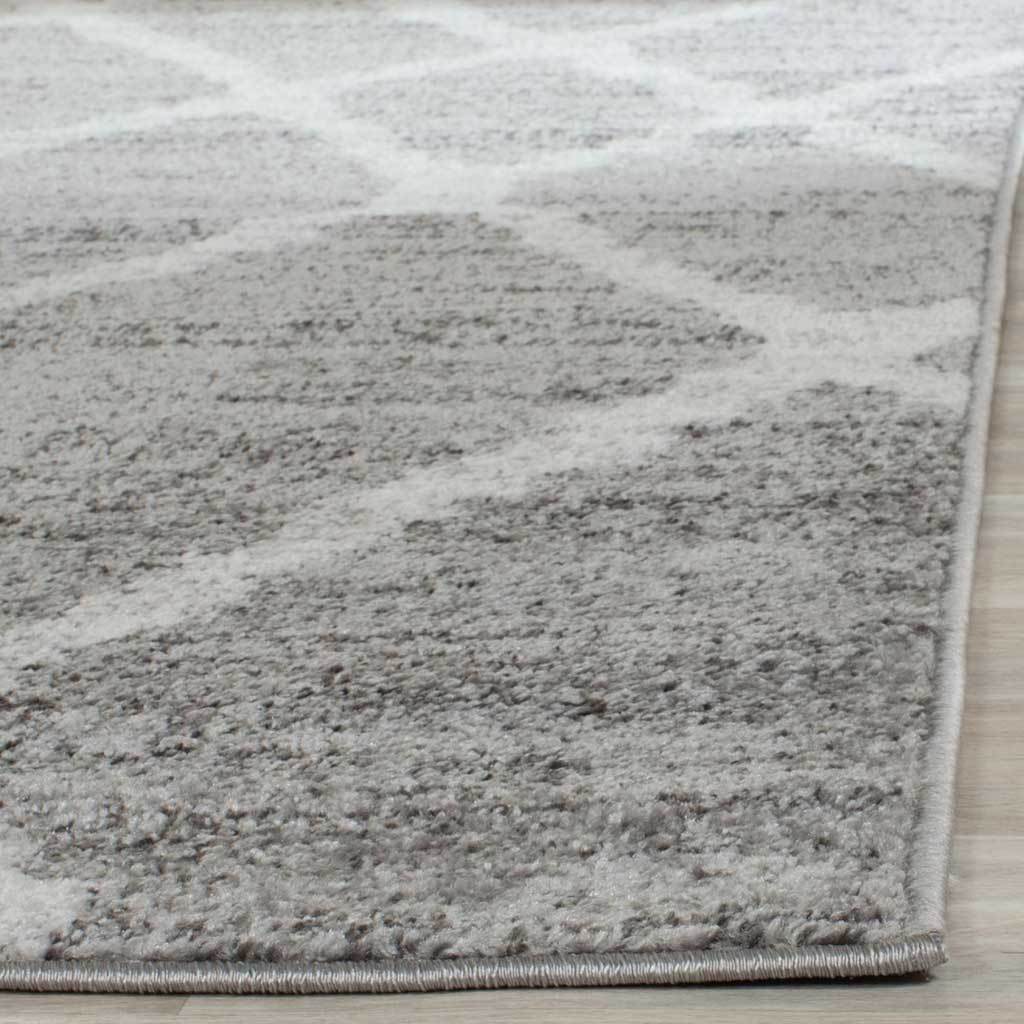 Textured silver-gray pile and ivory lattice lines meet neatly bound edges.