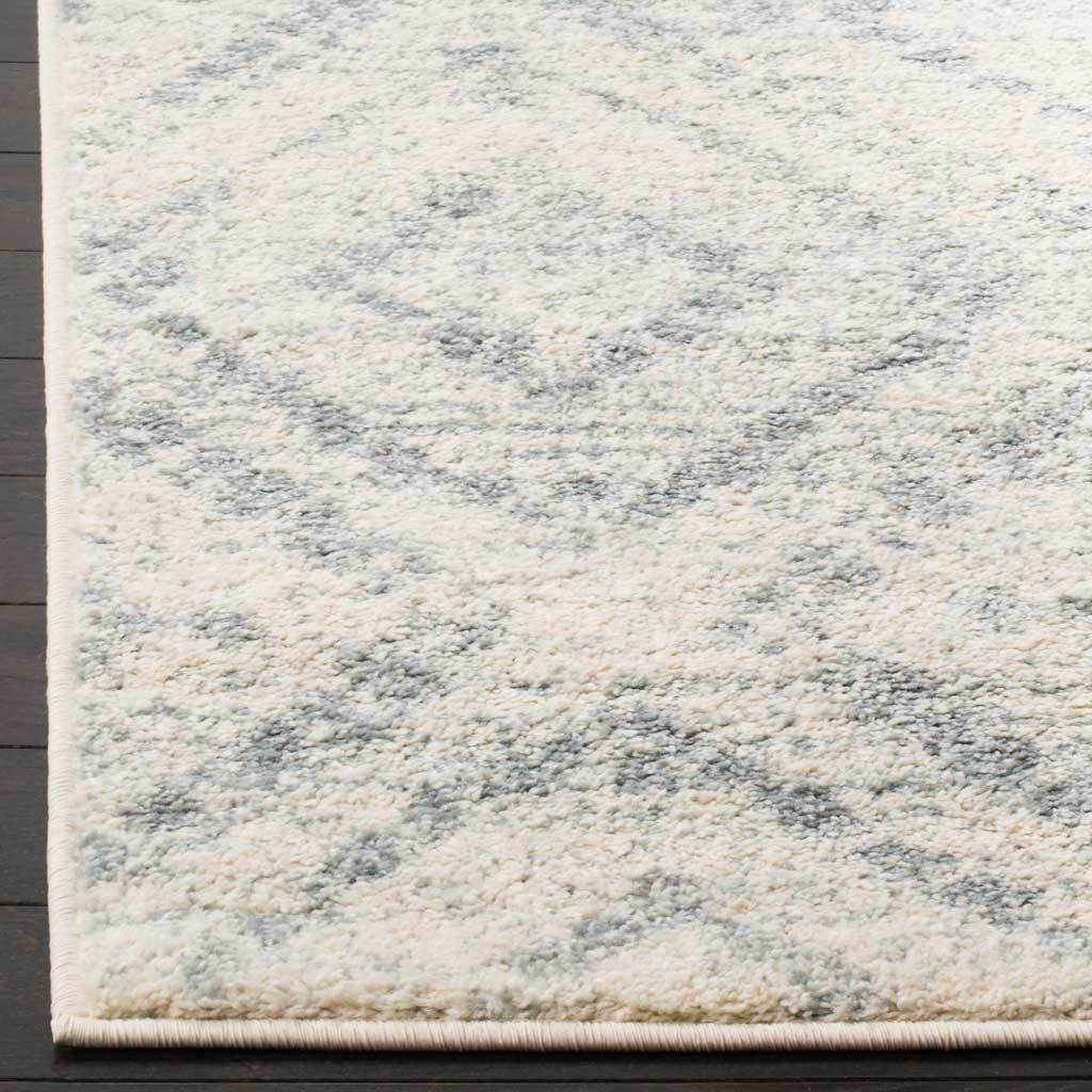 Soft ivory pile blends with faded blue geometric motifs along neatly bound edges