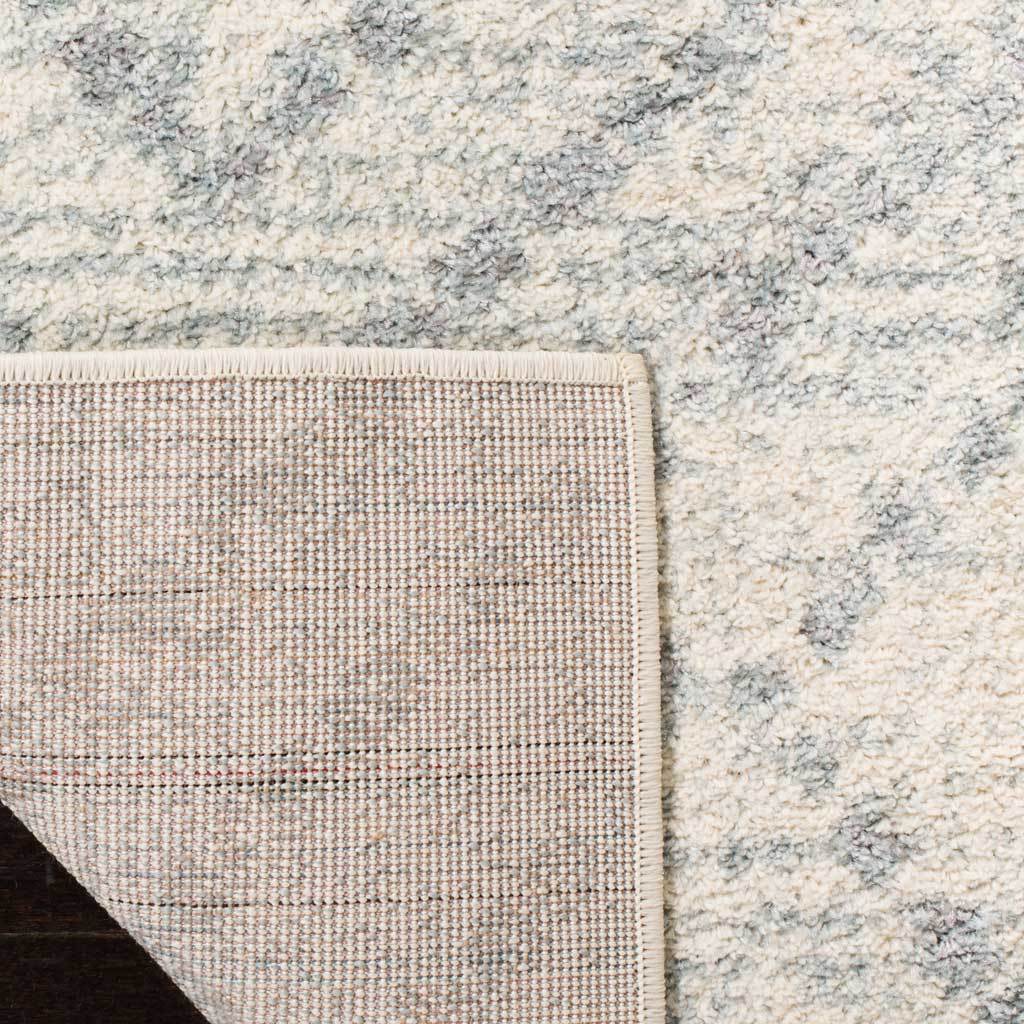 A folded corner reveals woven backing beneath the ivory and light blue pile