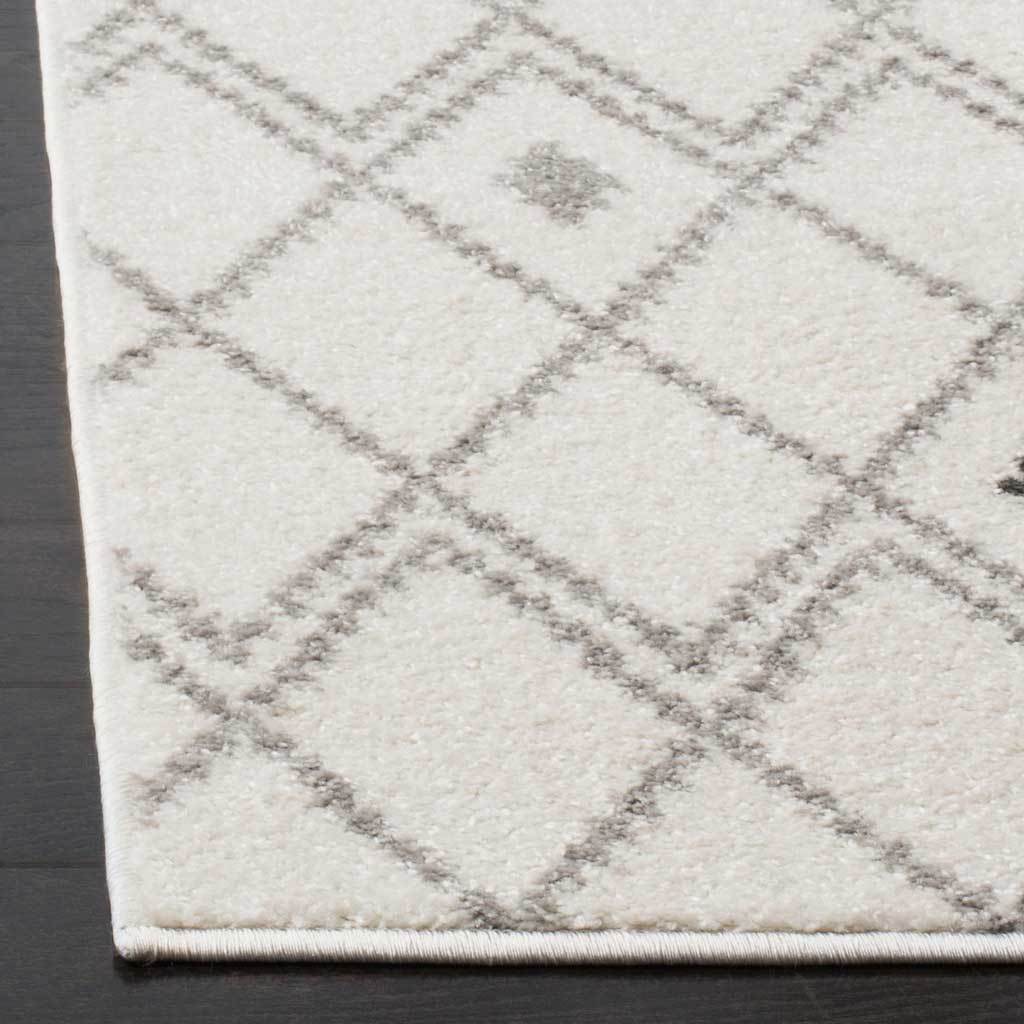 A bound corner frames soft ivory pile and gray diamond lines with subtle accent motifs.