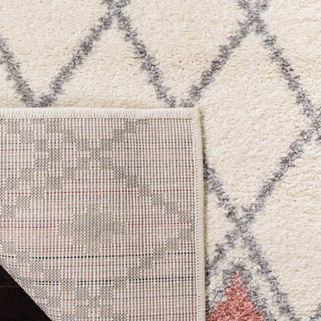 A turned-back corner reveals woven backing under ivory pile with colorful diamond accents.