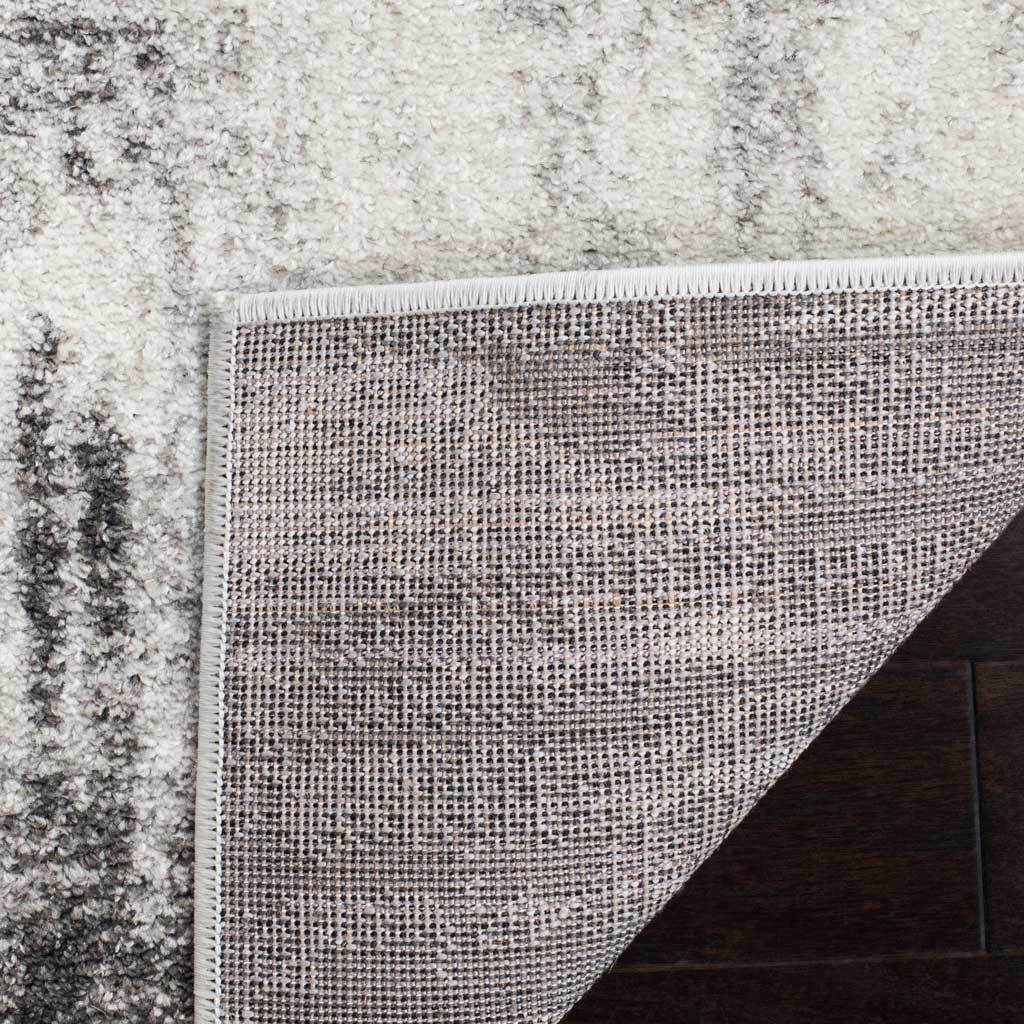 Woven backing and finished edges support the ivory and gray rug