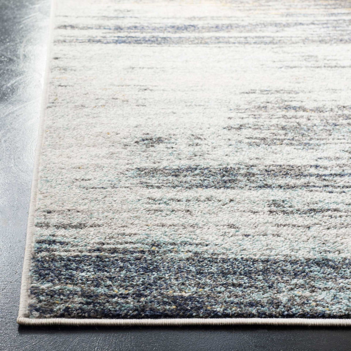 A neatly bound edge frames textured light gray pile with dark, painterly striations