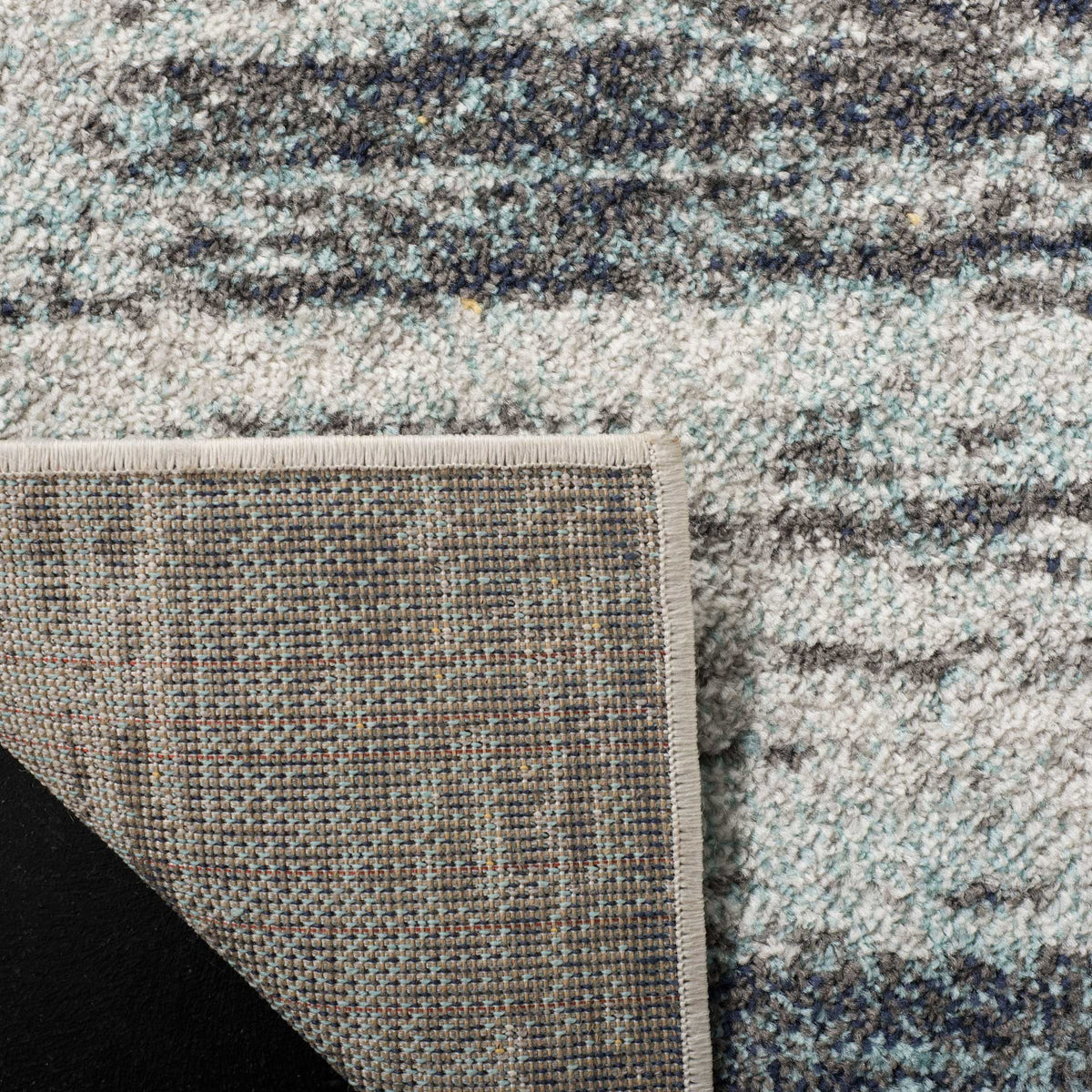 Woven jute backing supports the rug's mottled gray and black surface