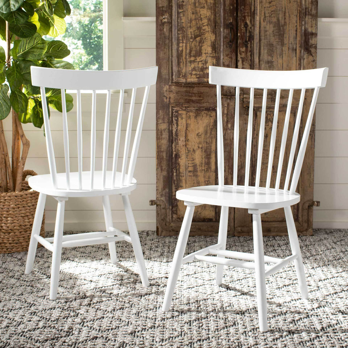 White wood chairs bring a fresh contrast to rustic cabinetry and a soft patterned rug.