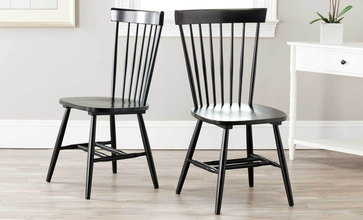A matching pair of black wood chairs balances graceful spindle backs with braced legs.