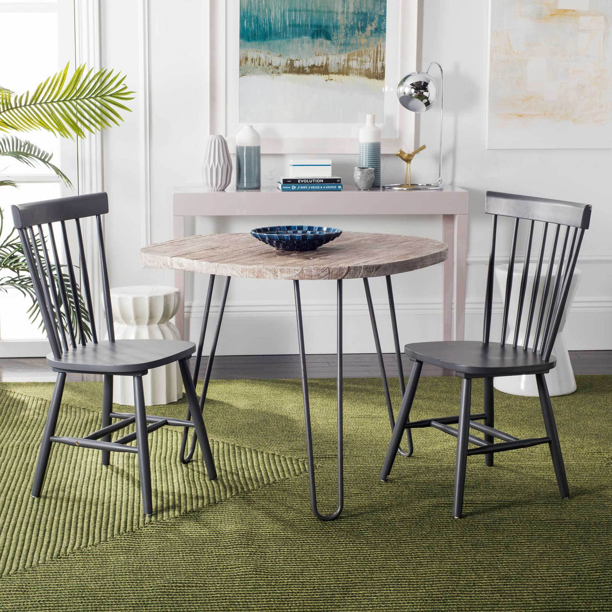 Charcoal gray wood dining chairs flank a round table with casual spindle-back style.