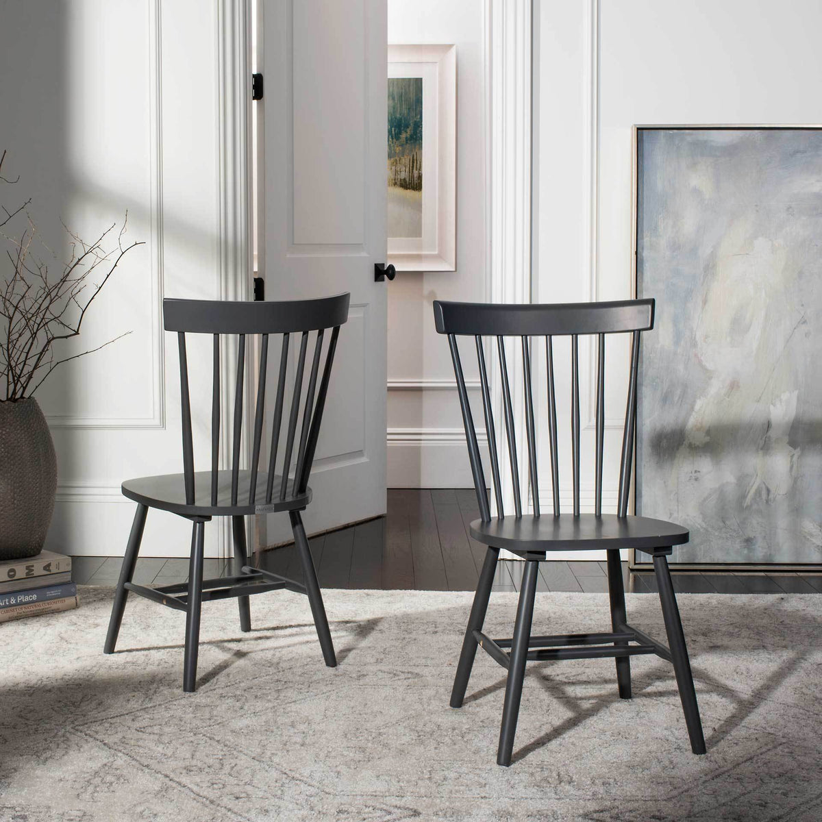 Two charcoal gray spindle-back chairs bring understated color and classic lines to a bright room.