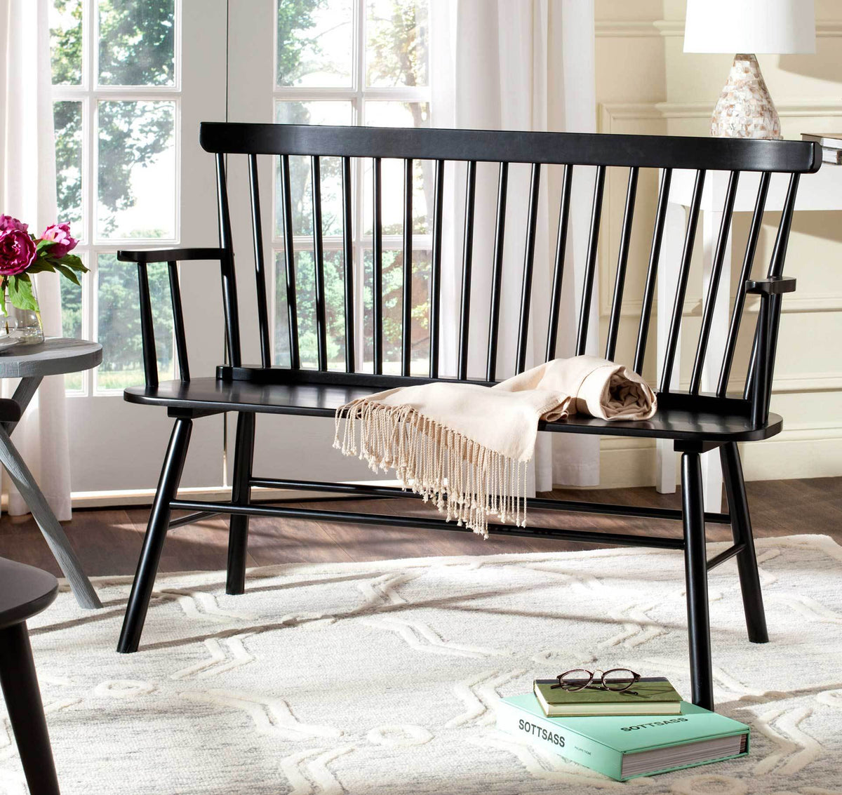 An elegant black settee offers spacious seating with airy spindlework and open armrests.