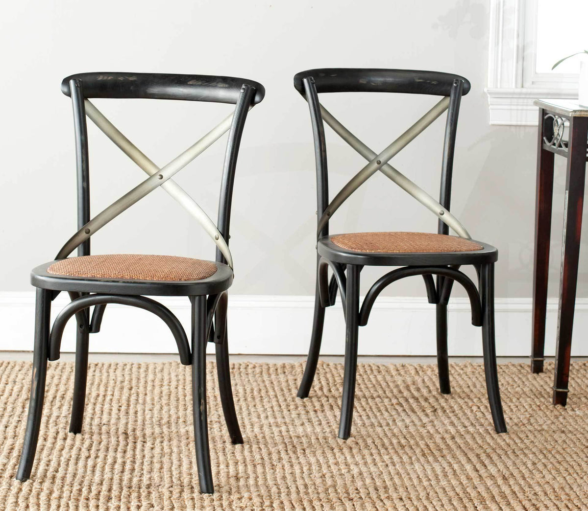Two black X-back chairs combine warm woven seats with sweeping arches for an inviting dining area.