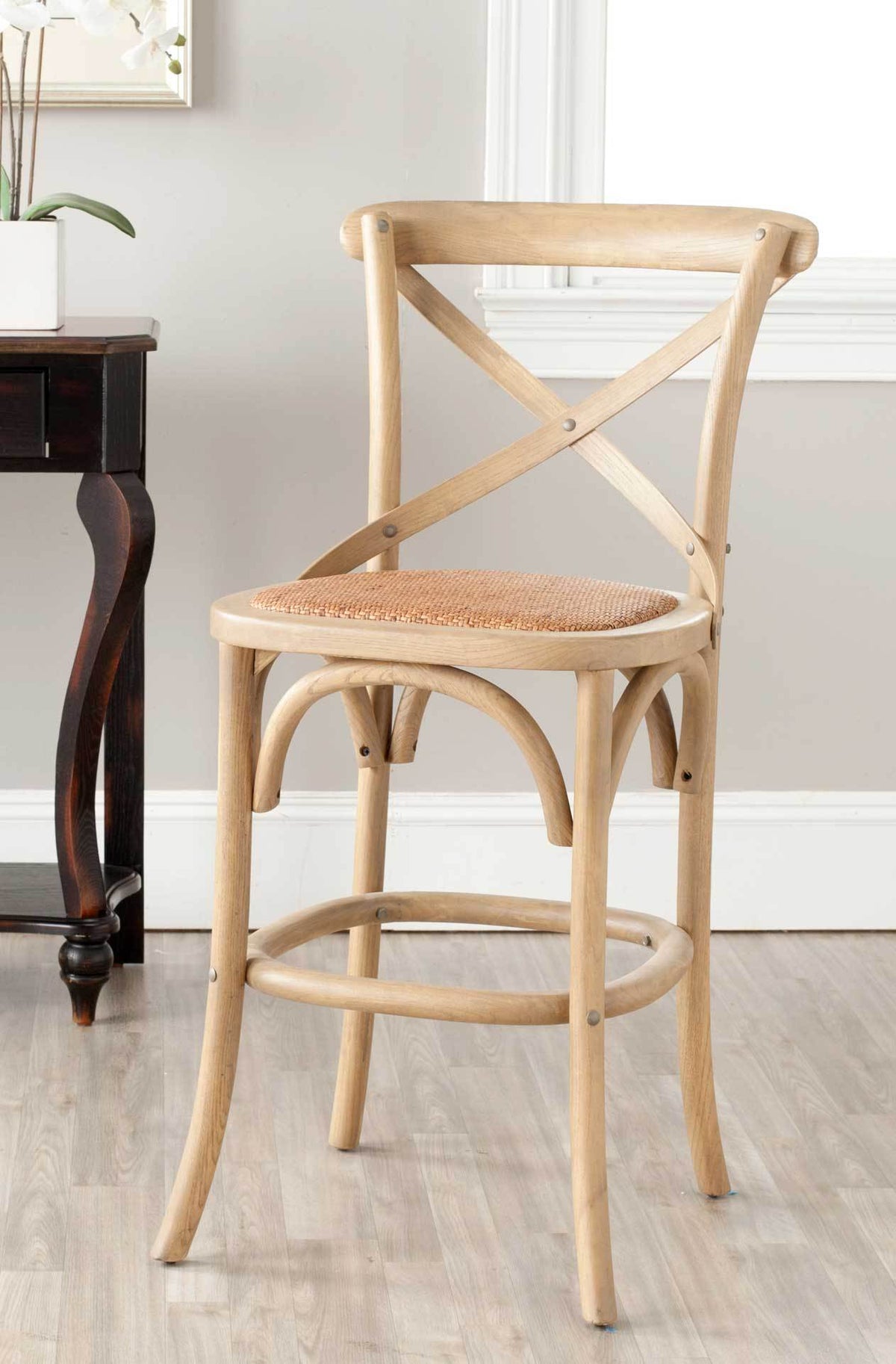 Weathered oak framing and a woven rattan seat give this cross-back stool easy farmhouse appeal