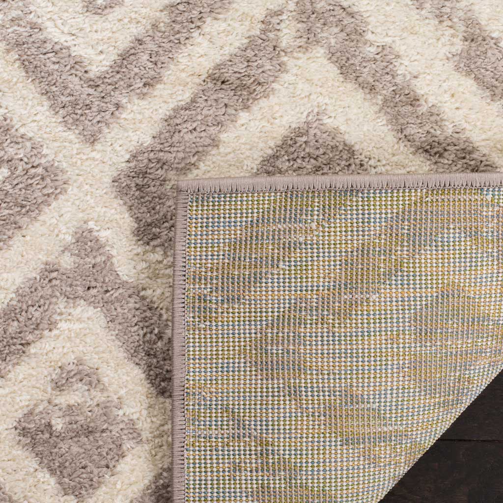 A woven backing supports the rug's soft ivory and mauve diamond pile