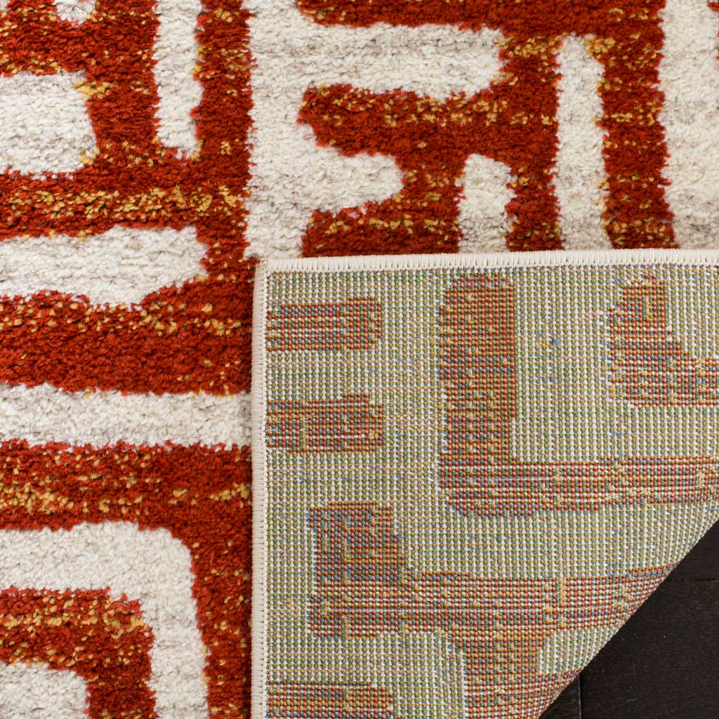A woven backing supports the plush ivory and terracotta patterned pile.