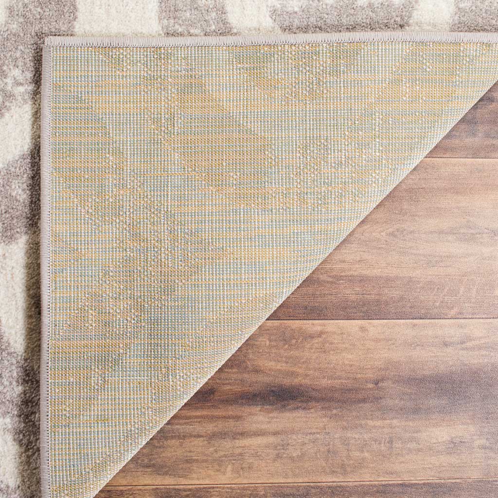 A folded corner reveals tightly woven backing beneath the rug's ivory and mauve patterned pile
