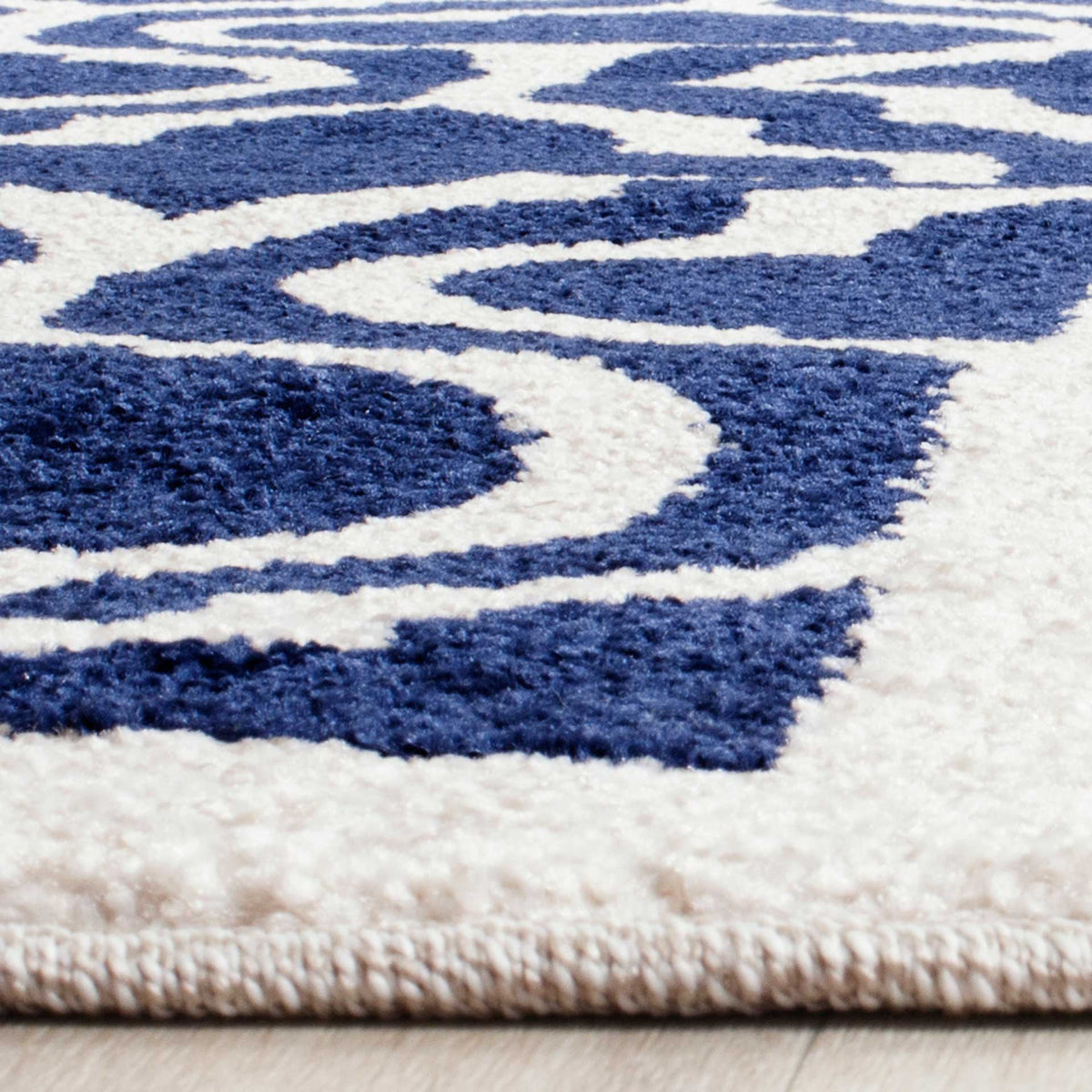 Textured navy pile contrasts with beige lattice lines and a neatly finished edge.