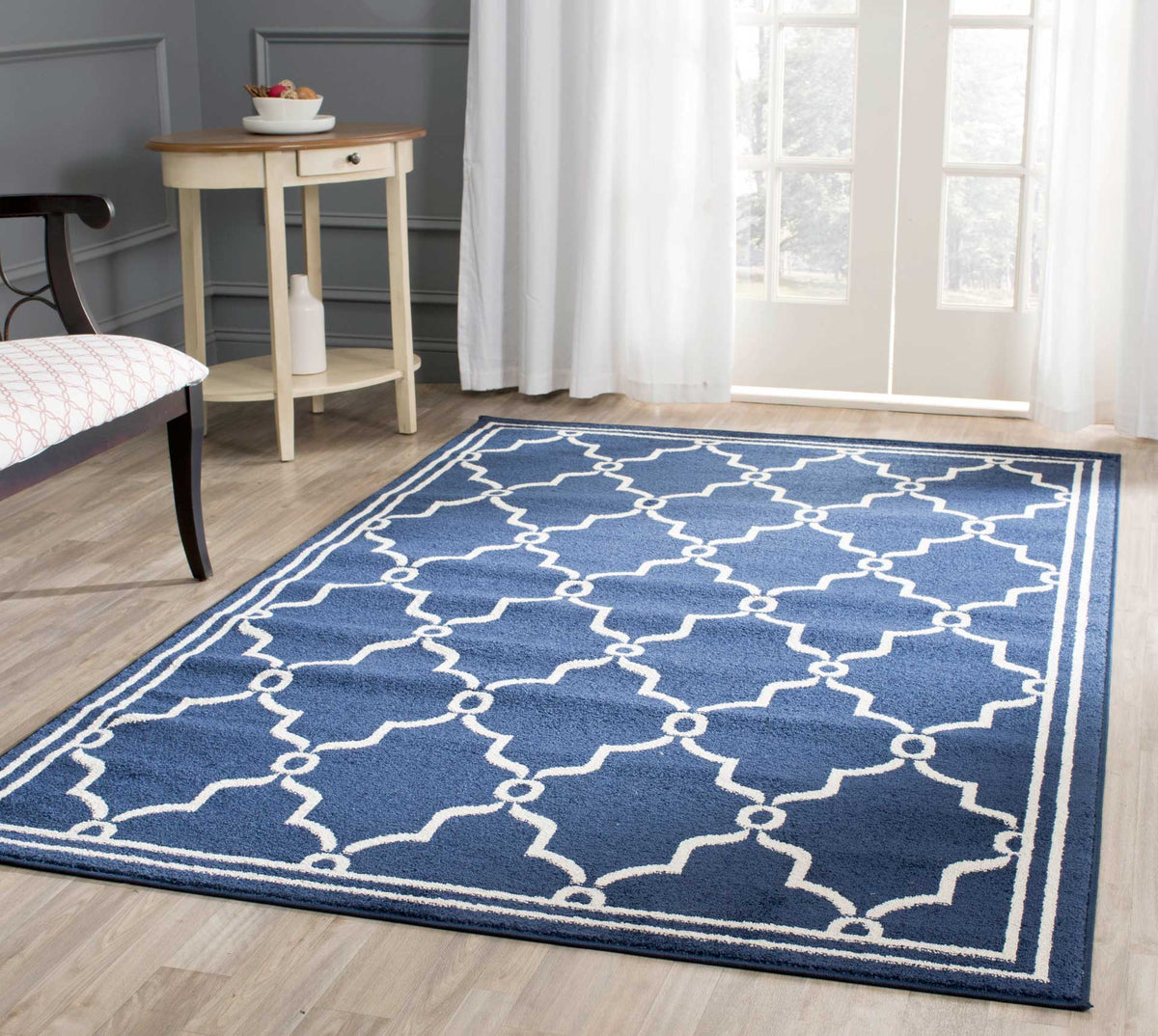 Navy trellis rug grounds a light wood floor with its striking beige pattern and border