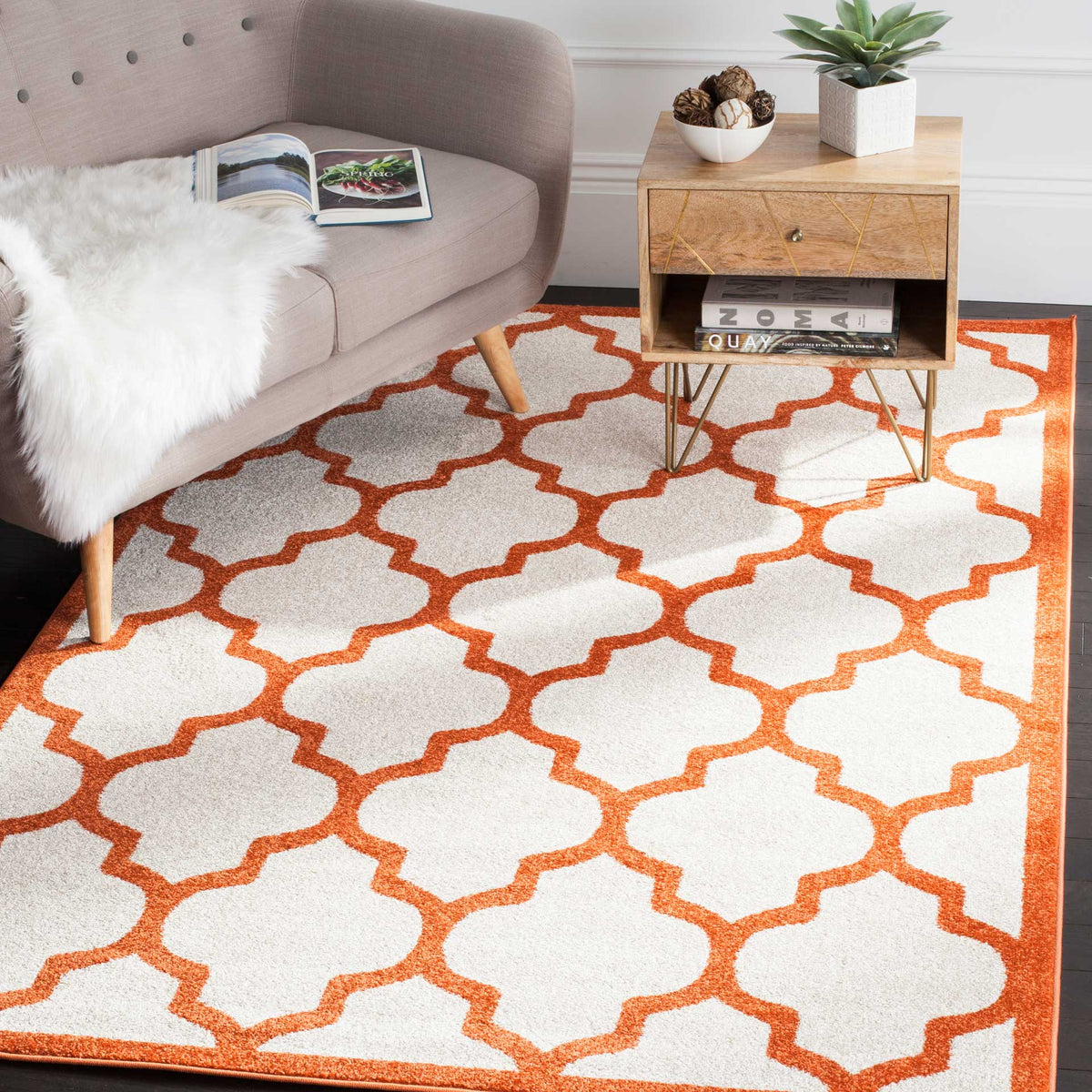 Beige area rug with a vivid orange trellis adds a lively touch beneath upholstered seating