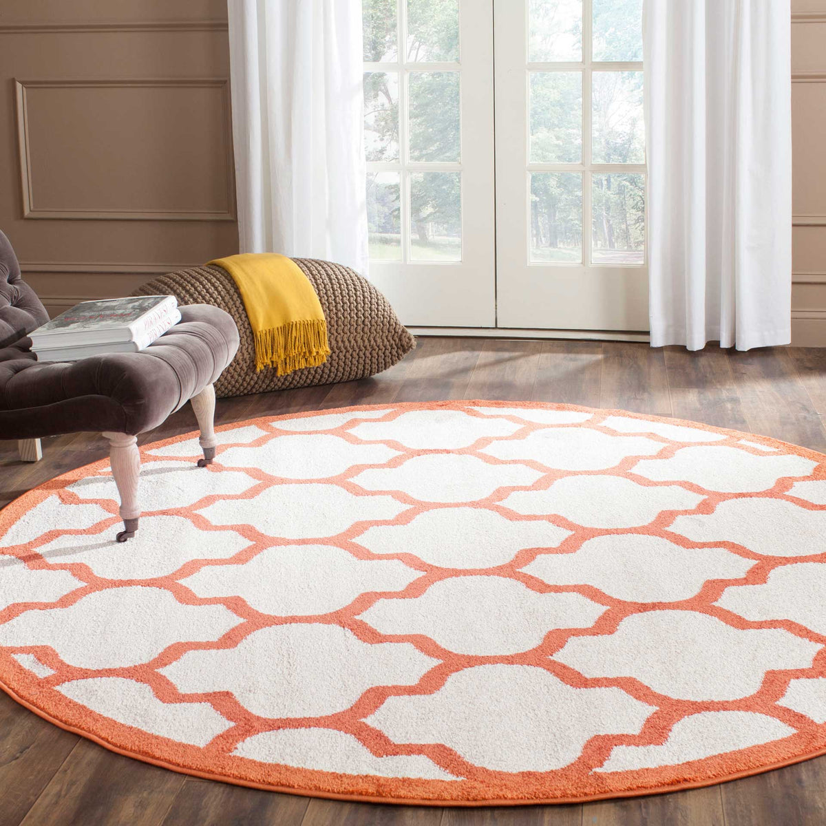 A bold orange trellis adds warmth to this round beige rug on dark wood flooring