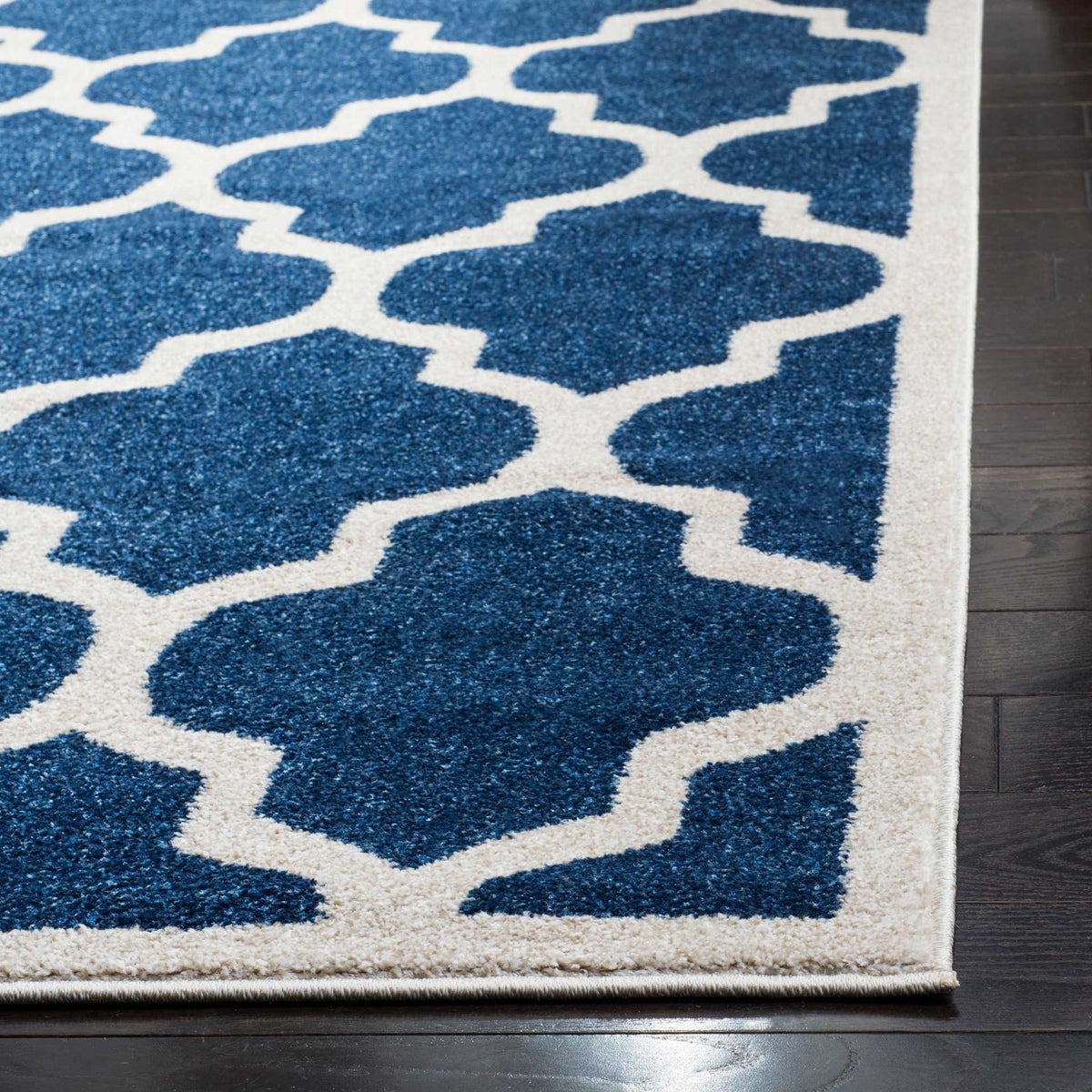 Navy pile and beige trellis lines meet at the rug's neatly bound corner
