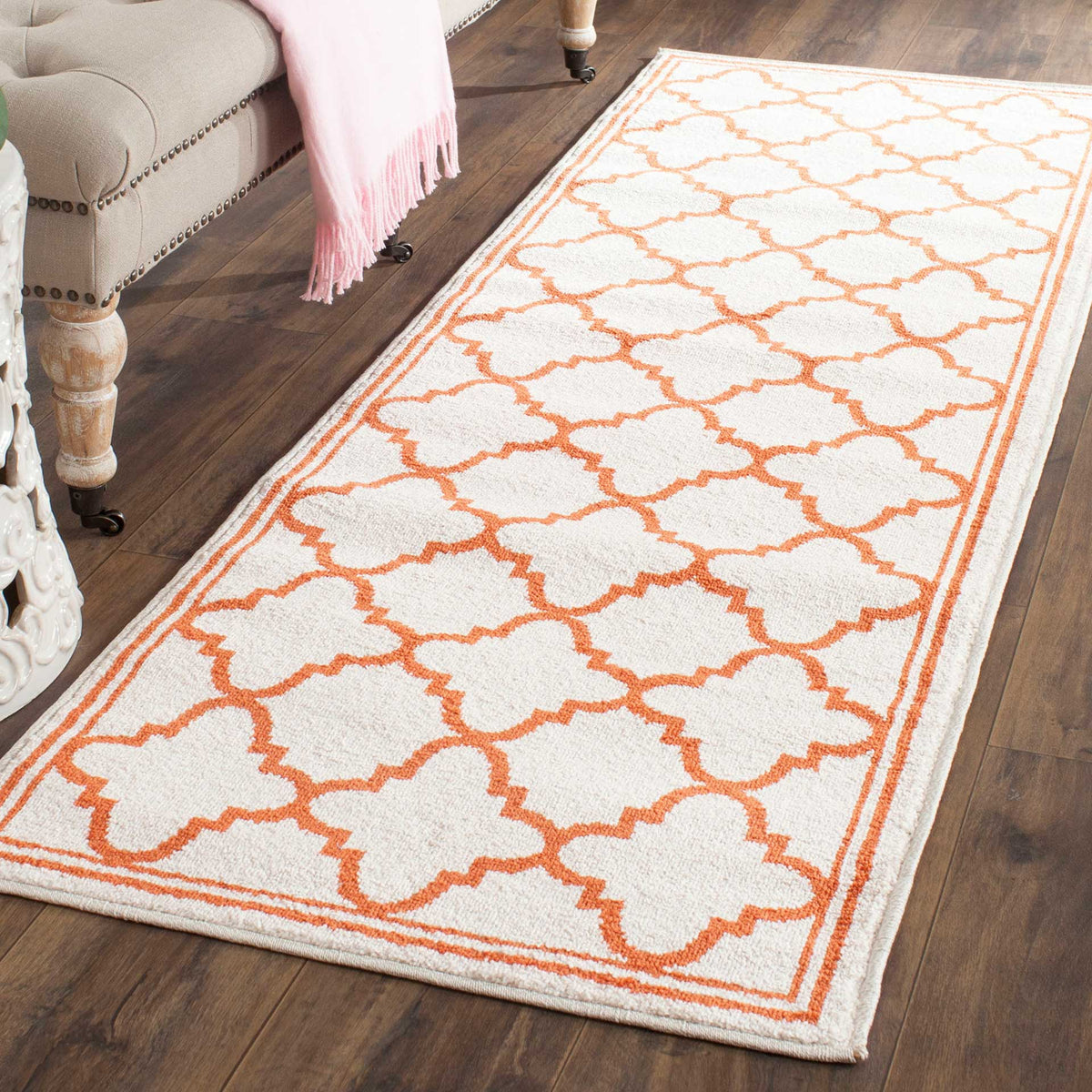 Bright orange latticework contrasts with this beige runner's textured surface and bound edges