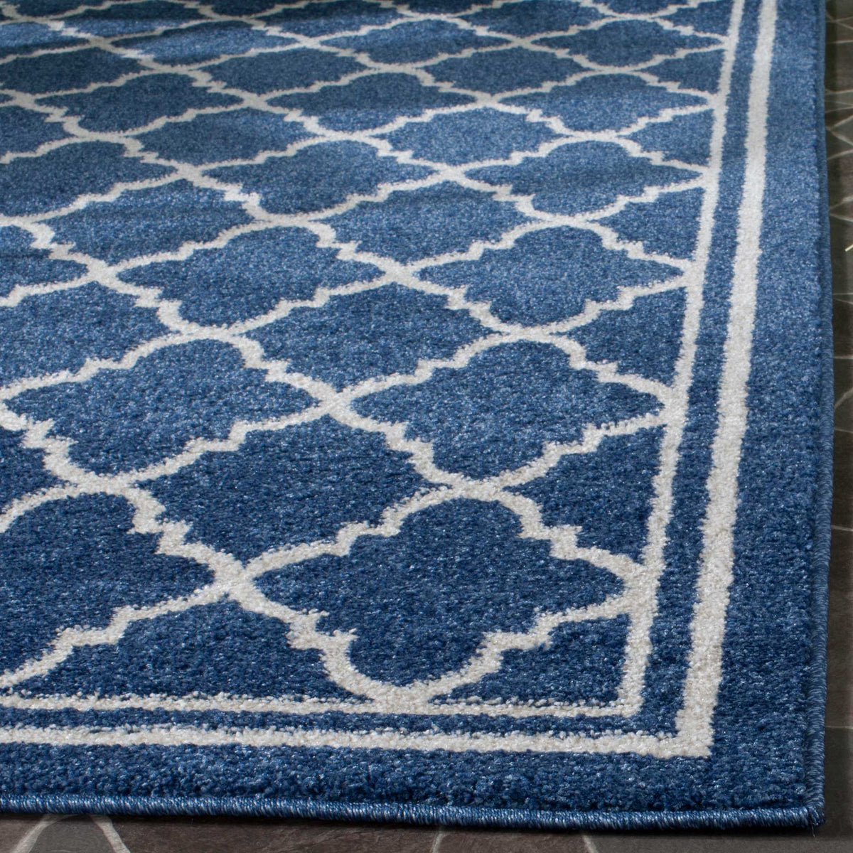 Rich navy pile, beige trellis lines, and a bound border give this rug a polished finish.
