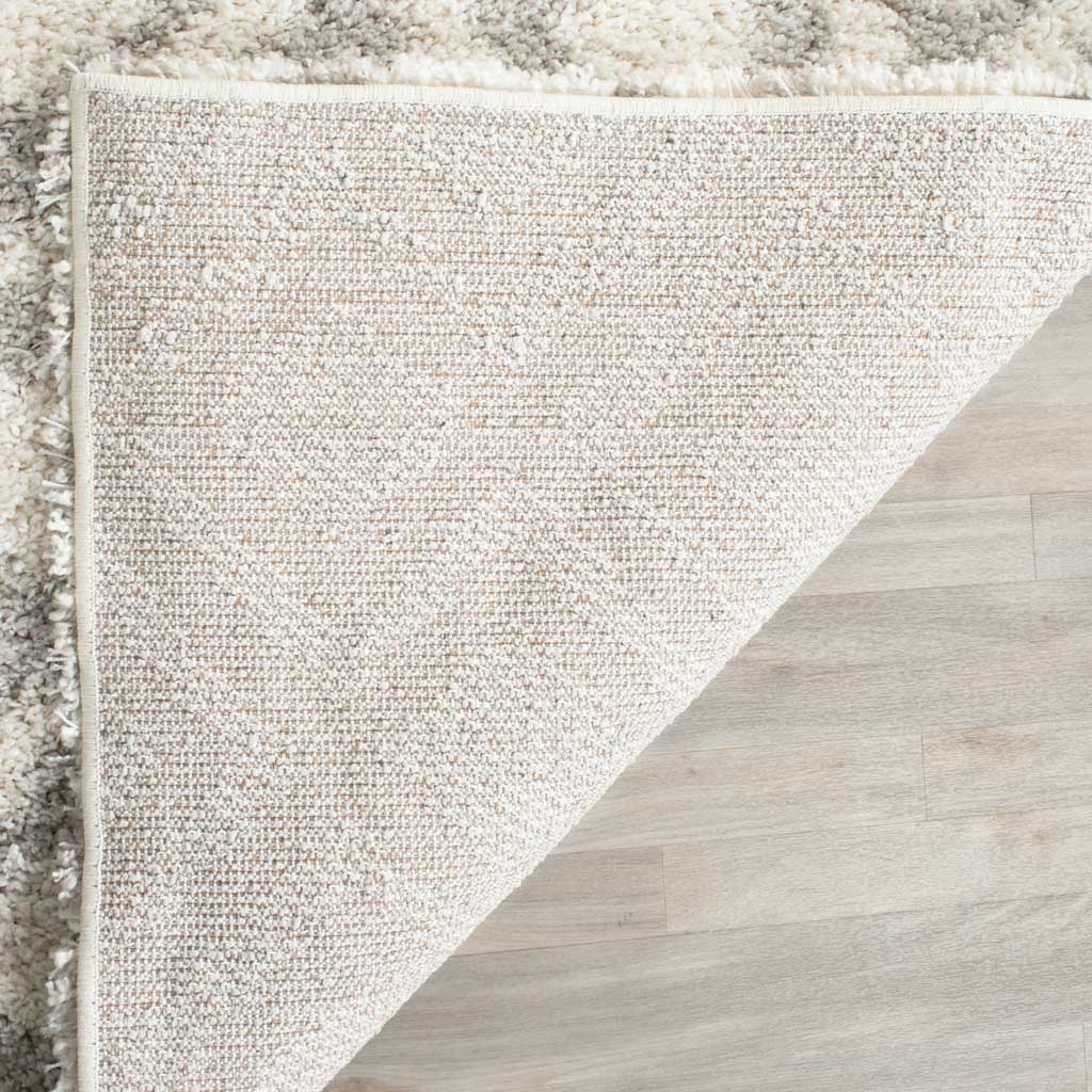 Neutral woven backing and secure edge binding support this thick ivory shag rug.