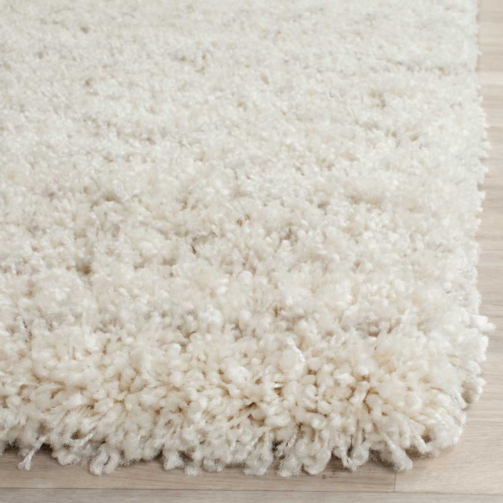 Long, soft ivory fibers gather at the rug's edge, showing its lofty shag pile.