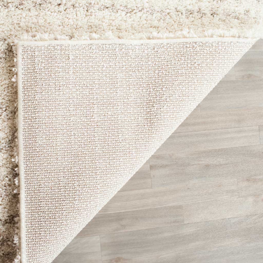 Light woven backing and a bound edge support the plush ivory and beige rug.